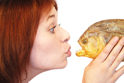Frau mit Fisch Frau hält Fischkopf an ihre Lippen